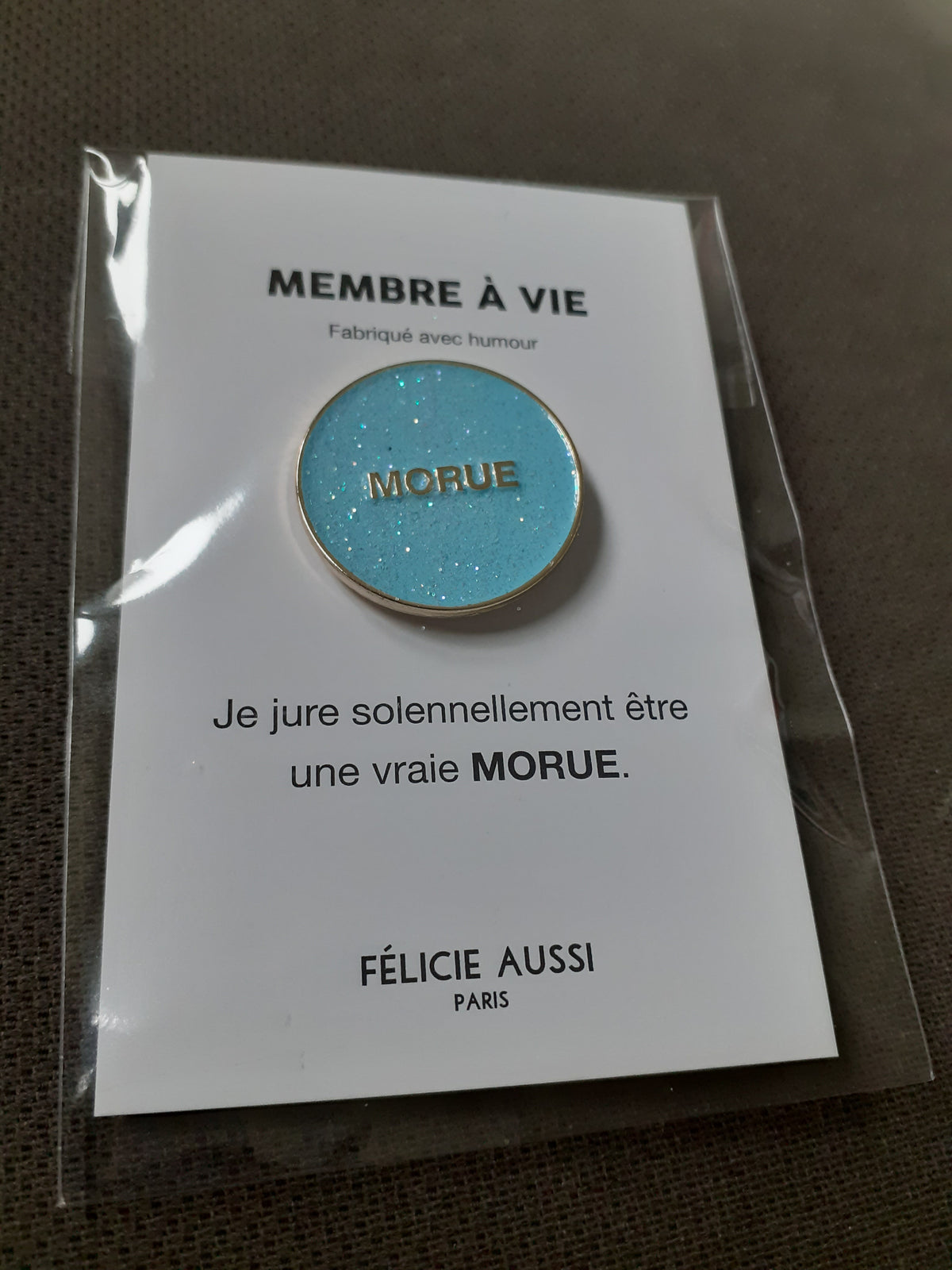 Félicie Aussi - Pin’s à paillettes - MORUE - rond turquoise