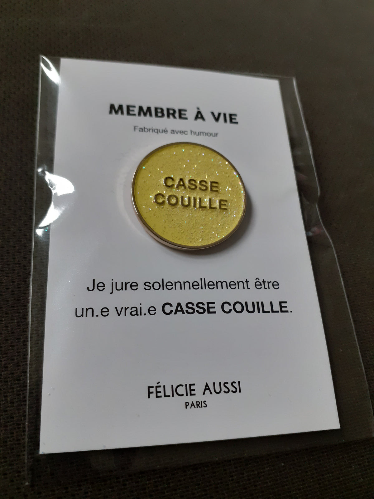 Félicie Aussi - Pin’s à paillettes - CASSE-COUILLE - rond jaune